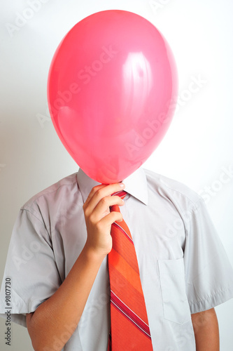 Young boy holding a red balloon in front of his face