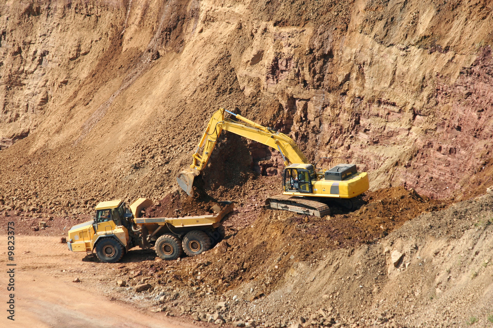 A Backhoe and dumptruck at rock quarry