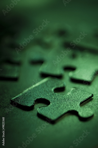Green jigsaw parts on dark background. Puzzle concept