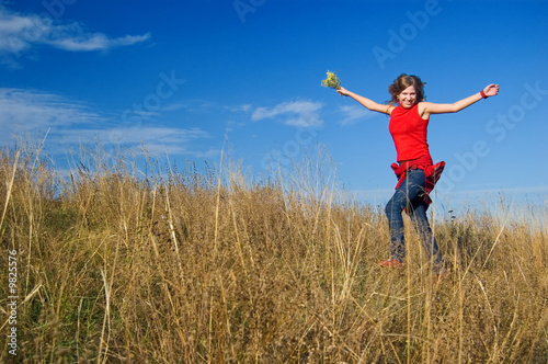 The girl in the red runs on an autumn field