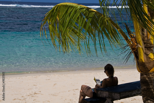 Young girl relaxing at a perfect beach with her book.