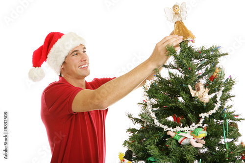 Tall young man placing the angel on the top of the tree. photo