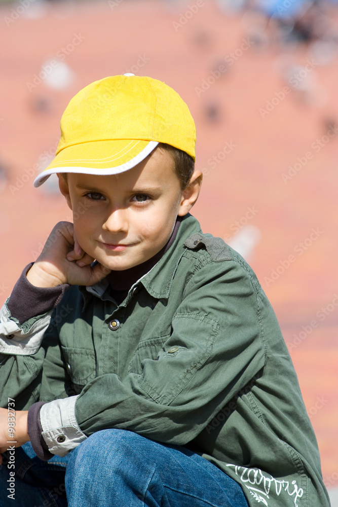 Cute boy with cap against blurred red background Cute boy with cap against blurred red background