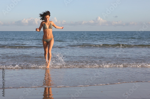 Shapely young female running out of the sea