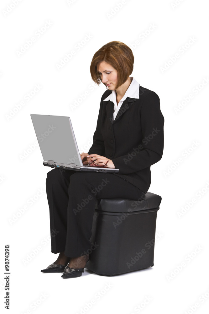 Businesswoman sitting on a pouffe and working on a laptop. Businesswoman sitting on a pouffe and working on a laptop.