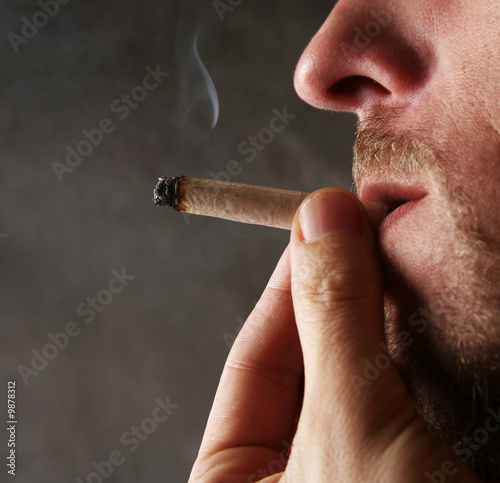 The adult the man smokes a cigarette