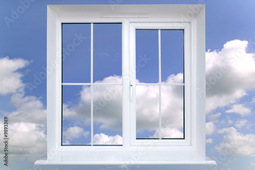 Window frame against a blue cloudy sky