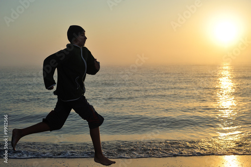 Young boy running on beach at sunrise