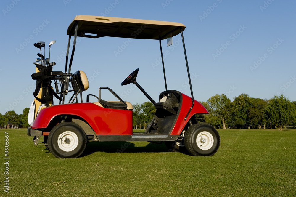 A red golf cart or buggy on a golf course with golf clubs etc