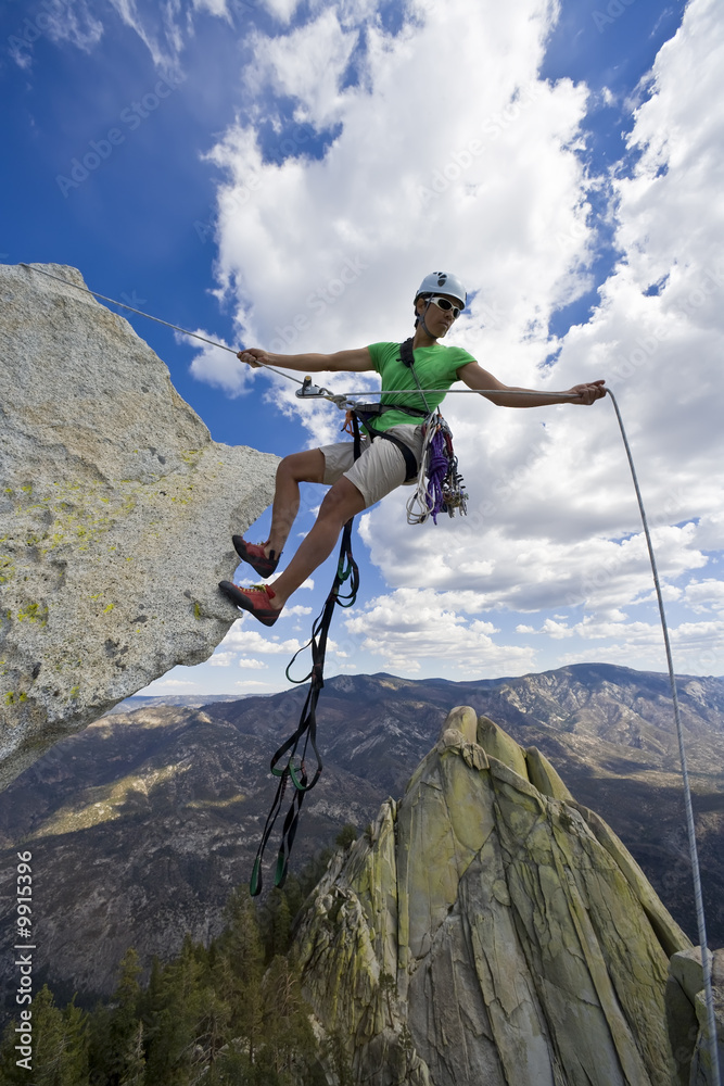 Climber rappelling from the summit of a rock spire.