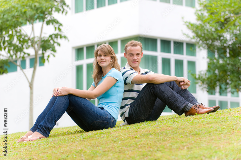 A young couple sitting in garden of their house A young couple sitting in garden of their house