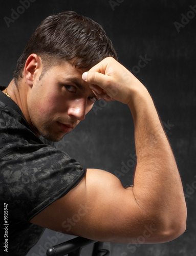 strong man showing his bicep against dark background © Sergii Shalimov