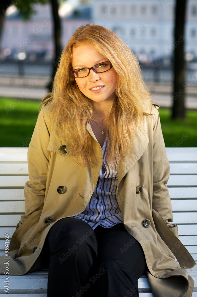 Portrait of a beautiful girl with glasses sitting on a park