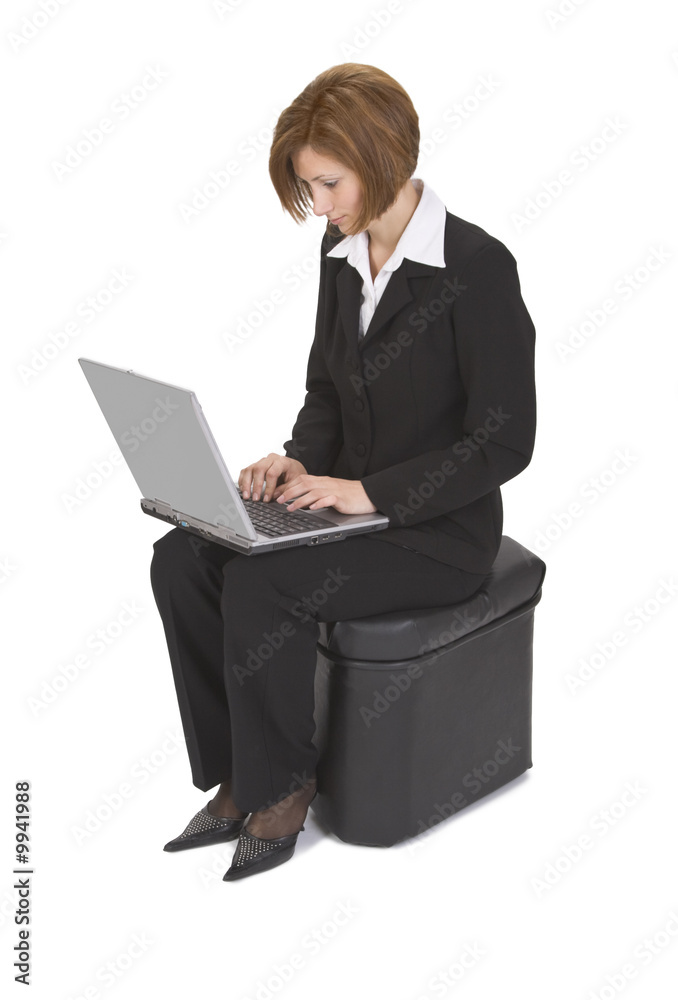 Businesswoman sitting on a pouffe and working on a laptop. Businesswoman sitting on a pouffe and working on a laptop.