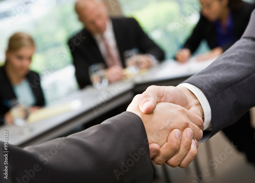 Close up of businessmen shaking hands in conference room