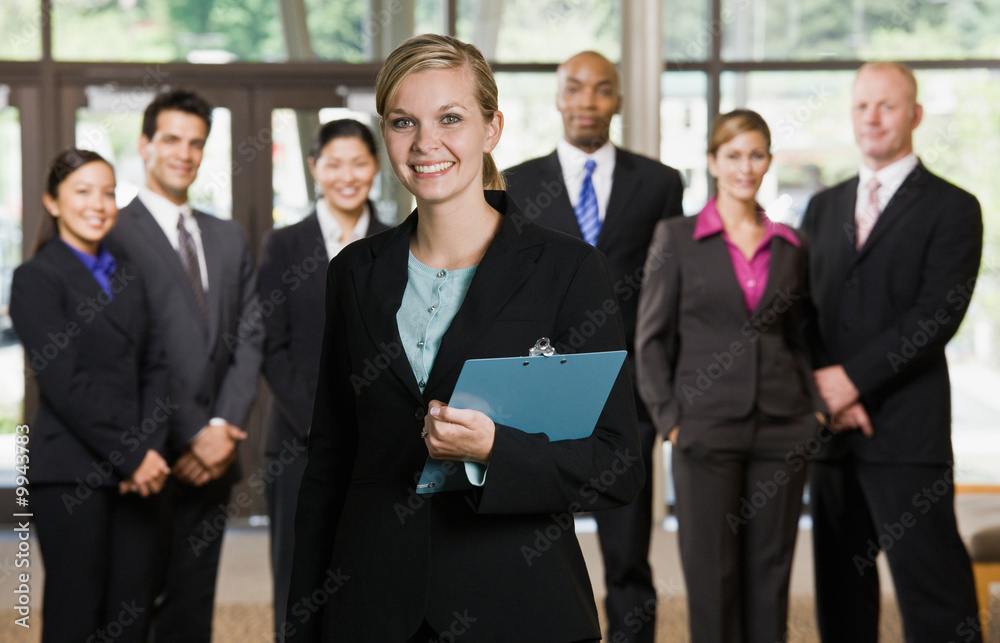 Confident businesswoman posing in front of co-workers