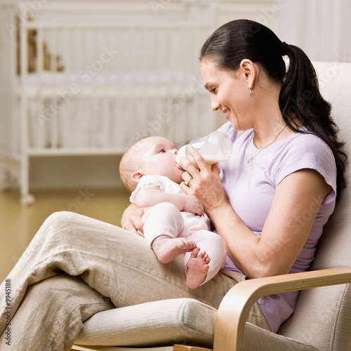 Devoted mother feeding bottle to hungry baby