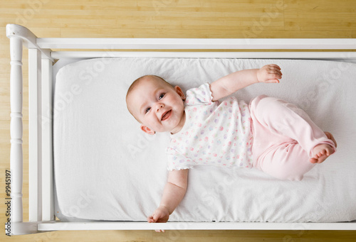 Happy, playful baby laying in crib