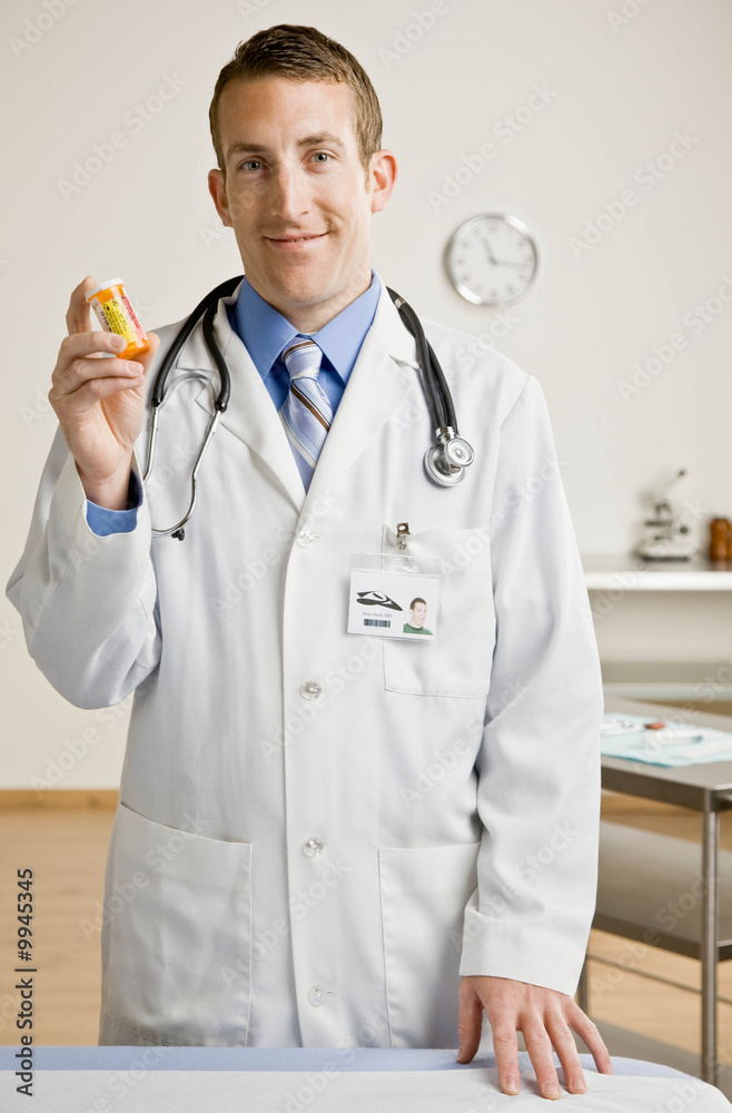 Doctor in lab coat and stethoscope holding prescription bottle Doctor in lab coat and stethoscope holding prescription bottle
