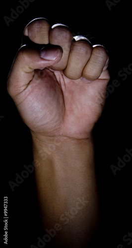 Vertical image of a fist in low key lighting with a rim-light. photo