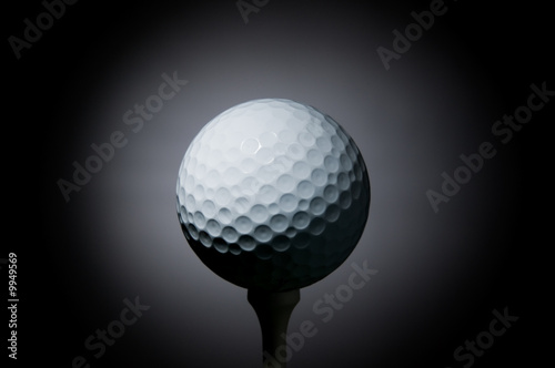 Golf ball on tee on black