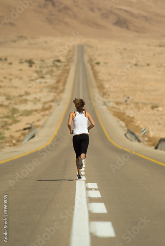 Young girl running over a desert highway.
