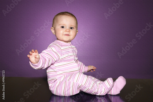 baby of ten months old seating down over a dark table