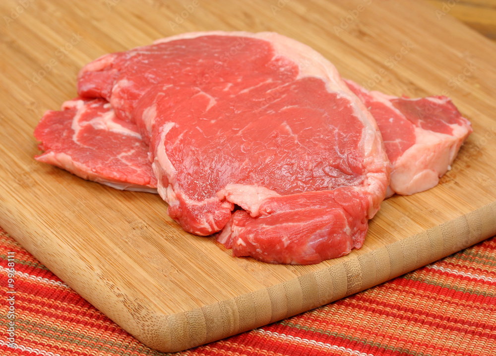 Two raw sirloin steaks on cutting board