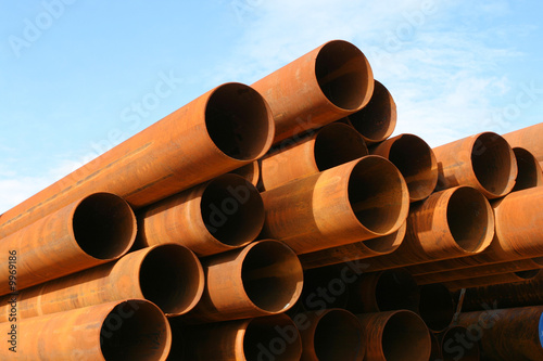 Rusty steel pipes, stacked against blue sky