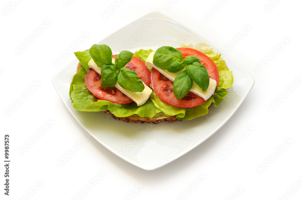 Sandwich of lettuce, tomato, camembert and fresh basil.