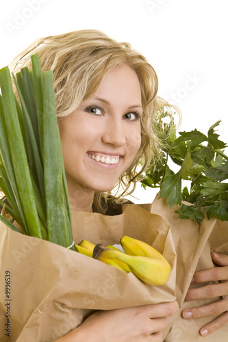 Lachende blonde Frau trägt Papiertüten mit Obst und Gemüse photo