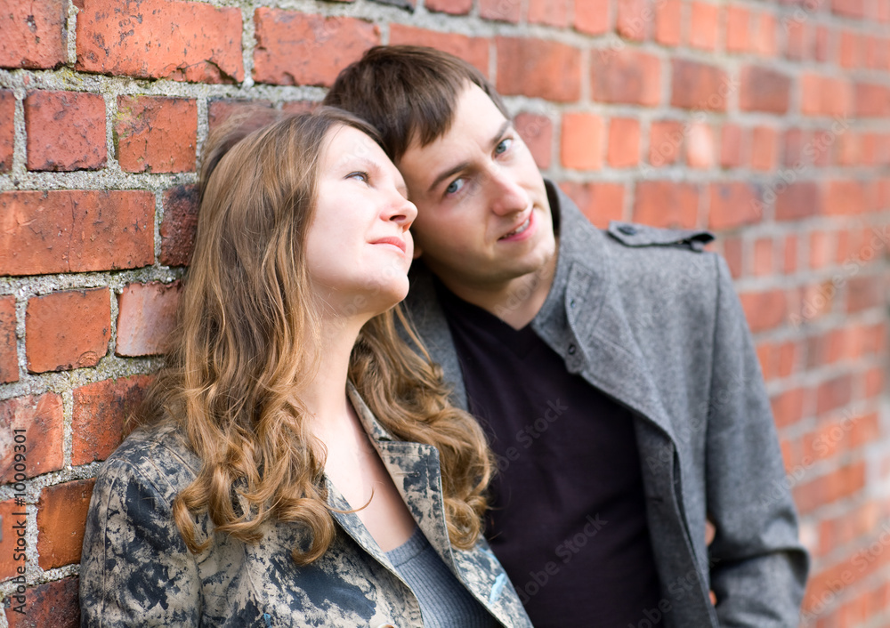 Romantic couple standing by old brick wall. Focus on girl.