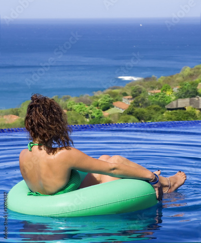 Young woman relaxes in a pool near the ocean