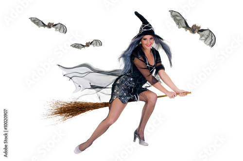 Young attractive Halloween witch flying on broom.