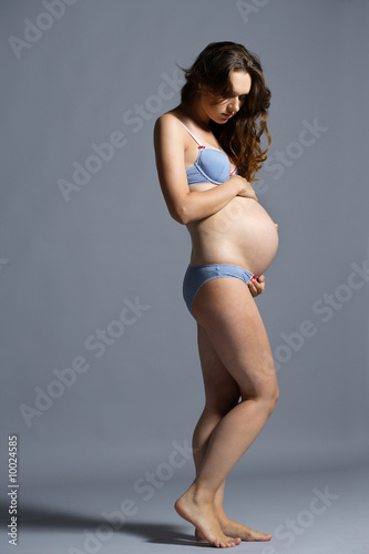 beautiful pregnant woman posing on grey