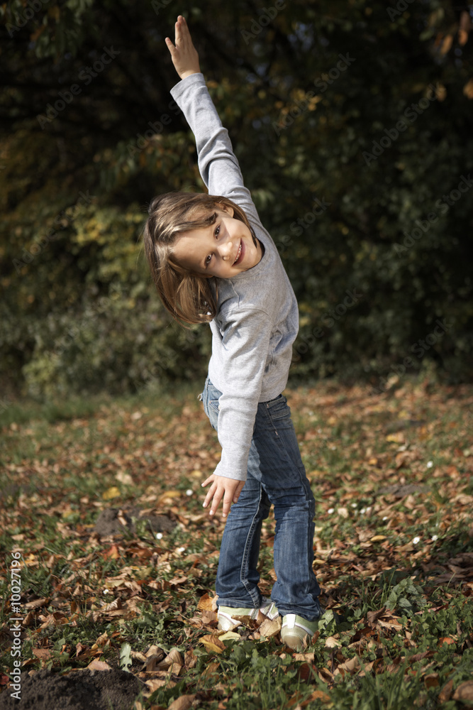 happy preschooler girl on autumn foliage meadow