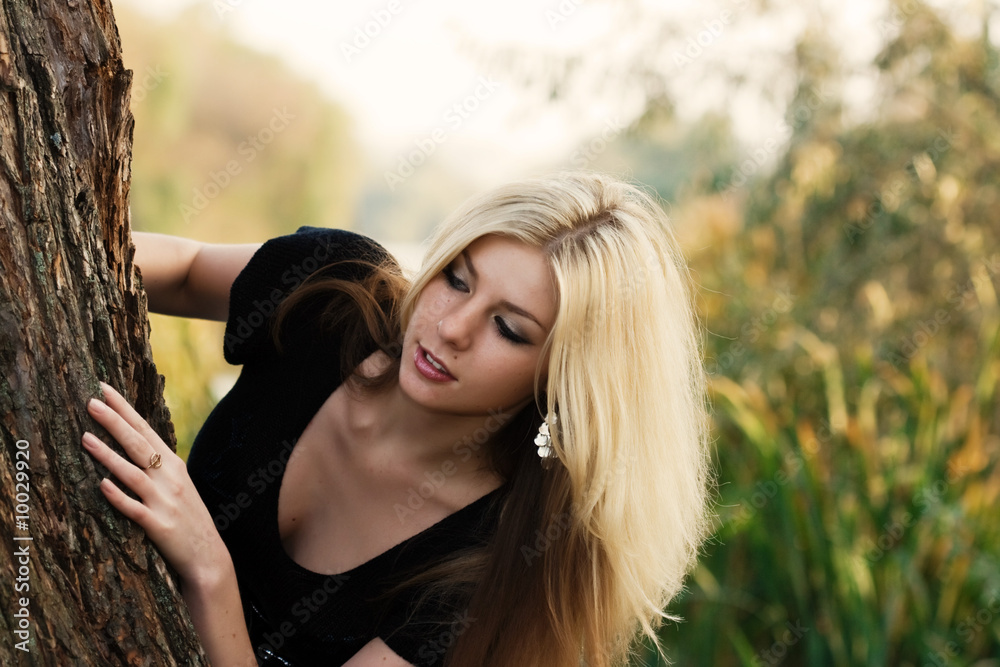 Naklejka premium Beautiful young woman hiding behind a tree