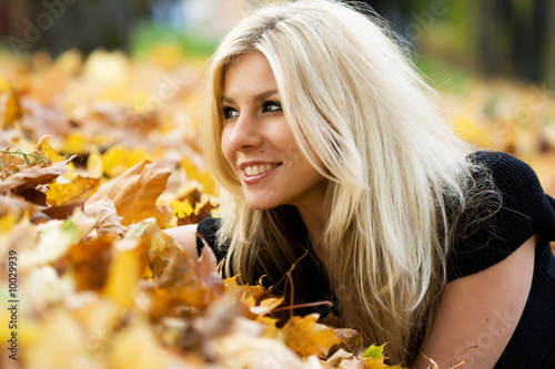 Young beautiful woman lying in the autumn park