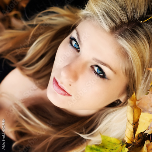 Portrait of young woman lying on autumnal leaves