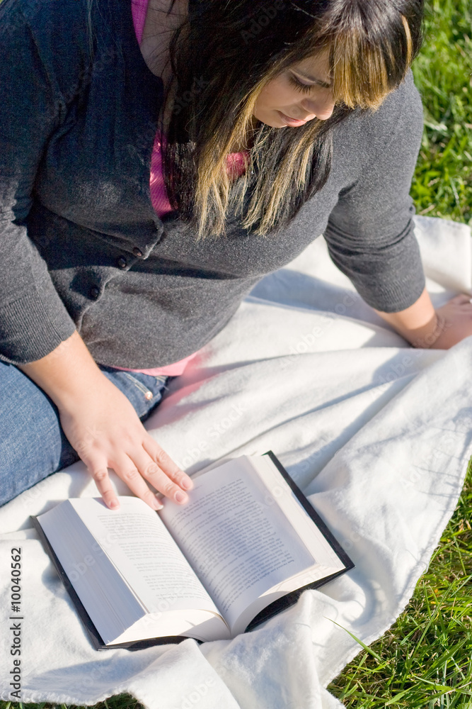 Obraz premium A young woman with highlighted hair reading a book.