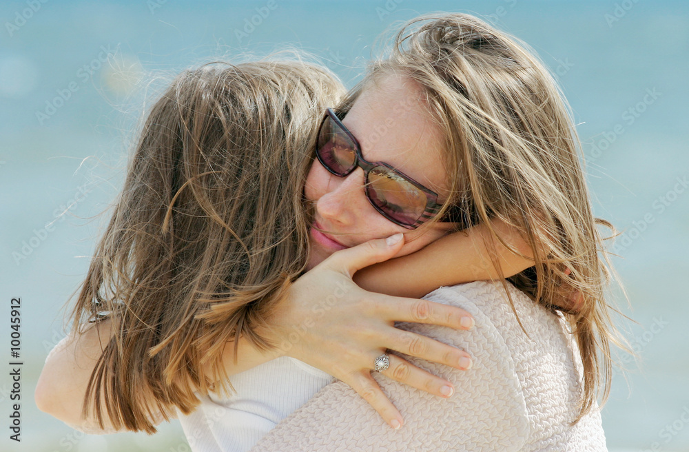 petite fille dans les bras de sa maman sur la plage Photos | Adobe Stock