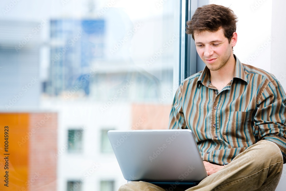 Businessman sitting in office window and working on laptop Businessman sitting in office window and working on laptop