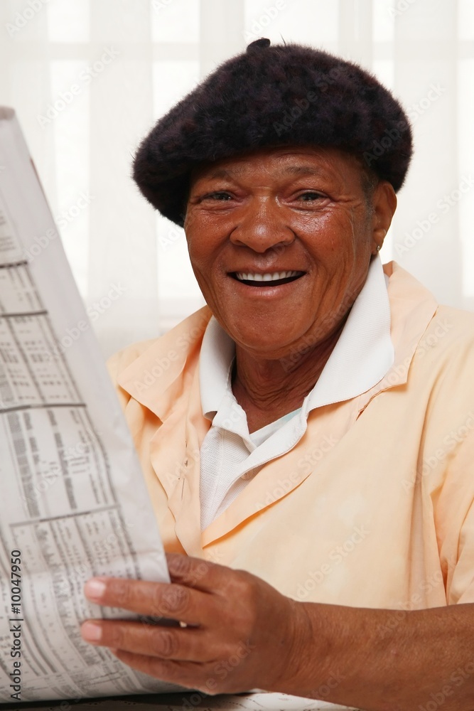 Obraz premium African woman reading a newspaper and smiling