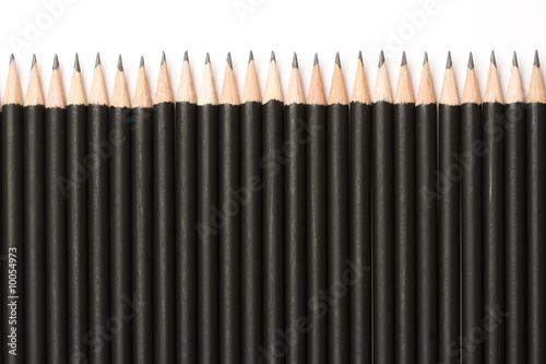 Black pencils lined up on white background.
