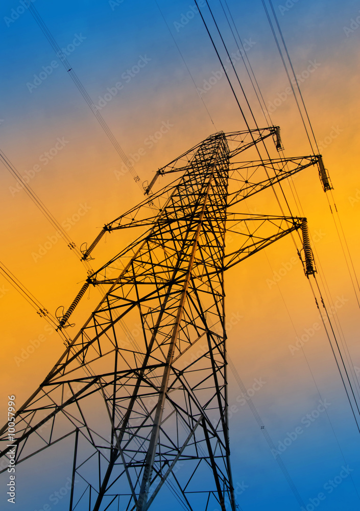 Silhouette of electricity pylon against orange and blue sky