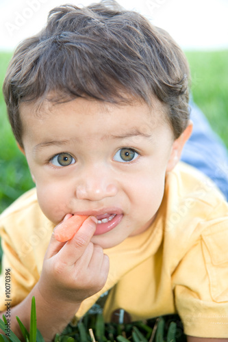 Adorable little boy snacking on a carrot