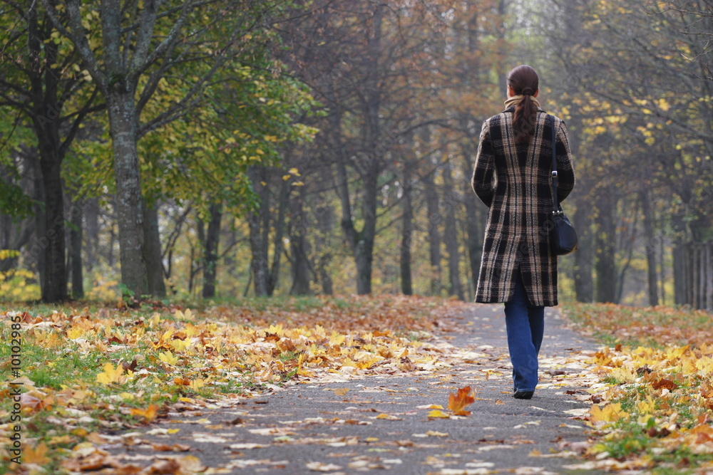 Fototapeta premium Young woman walking in an autumn park