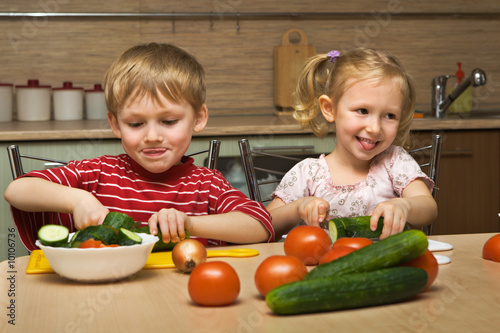 Small boy and girl cut vegetables