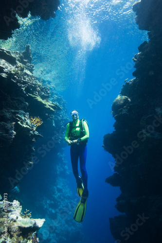 scuba diver swimming between two coral cliffs  underwater