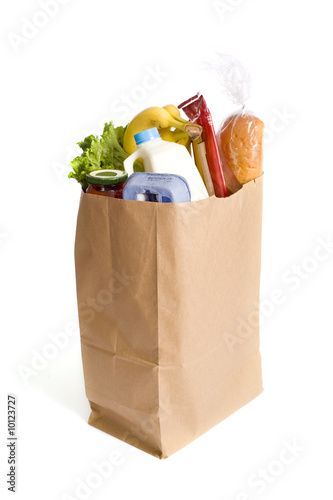 A brown kraft bag full of groceries including, milk, eggs
